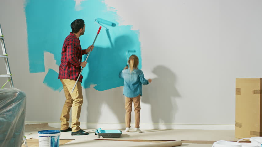 Young Father is Showing How to Paint Walls to Cute Small Daughter. They Paint with Rollers that are Covered in Light Blue Paint. Room Renovations at Home. Royalty-Free Stock Footage #1023188104