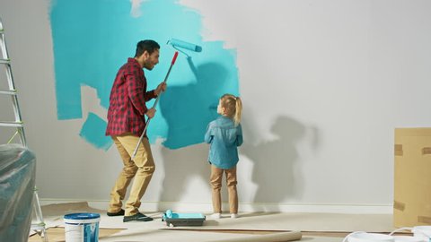 Young Father is Showing How to Paint Walls to Cute Small Daughter. They Paint with Rollers that are Covered in Light Blue Paint. Room Renovations at Home.