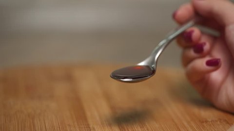 close up: vanilla or maple syrup in a spoon
