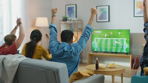 At Home Diverse Group of Sports Fans Watches Important Soccer Match on TV, They Cheer for the Team, Celebrate Victory after Team Scoring Beautiful Winning Goal.