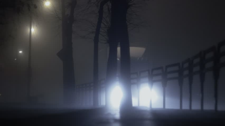 Bright light from headlamps of cars shines through the fog on a road at night, poor visibility due to haze | Shutterstock HD Video #1023198661