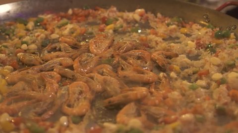 Cooking spain paella with rice, shrimps and vegetables in pan close up. Process preparation traditional spanish dish paella. Cook making spain paella at pan. Food concept. Healthy nutrition