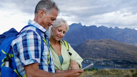 Active fit Caucasian male and female senior travelers enjoying their hiking and planning tour reading map of The Remarkables Lake Wakatipu New Zealand 