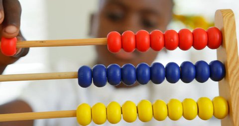 Front view close up of little African American boy studying with abacus in a comfortable home. Close-up of African American boy counting abacus beads.