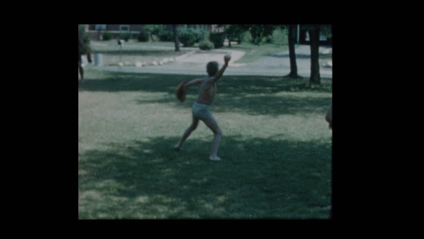 1960 Father and son toss a baseball when antique car drives by