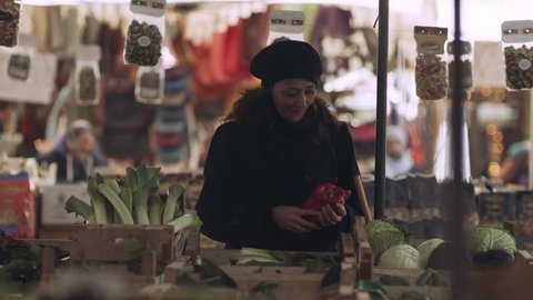 A content Italian woman walking through a busy food market looking at different fresh produce and ingredients in Rome, with soft natural lighting. Wide shot on 8k helium RED camera. 