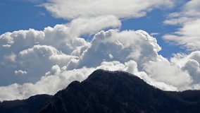 Blue sky with clouds timelapse. Clouds are moving and rolling on a top of mountain. Concept of time, atmosphere, weather, forecast, cyclone
