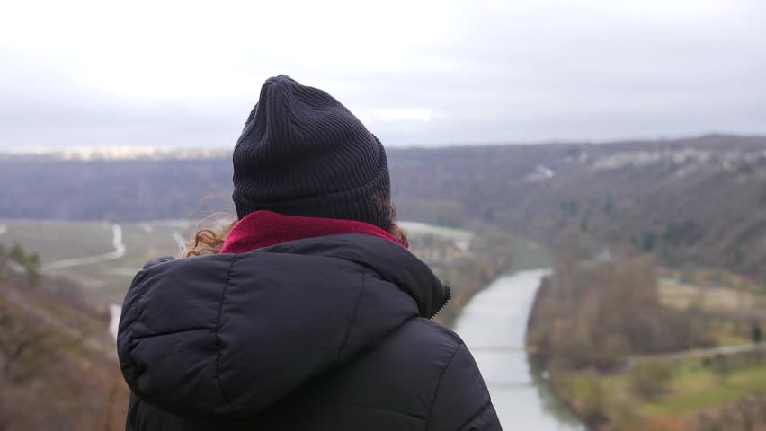 young girl watching landscape on a windy day. River and nature in the background
