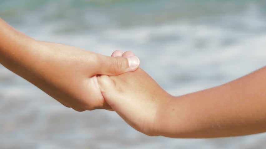 Children hold hands in front of sea. Summer vibes.