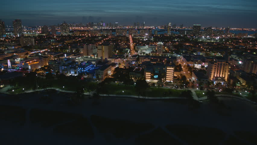 Aerial Reveal illuminated night view of South Beach luxury Art Deco hotels and Condominiums Ocean Drive Atlantic Coastline Miami Florida USA