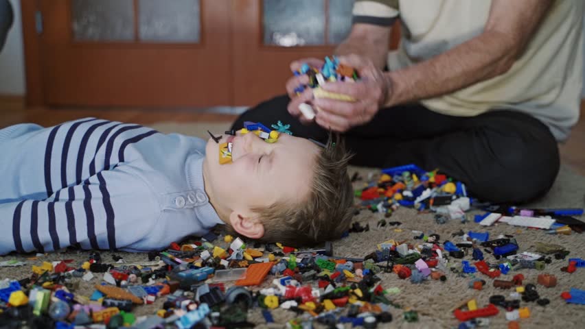 Excited boy and his grandfather playing with lots of colorful plastic toys. Educational toys. Slow motion
