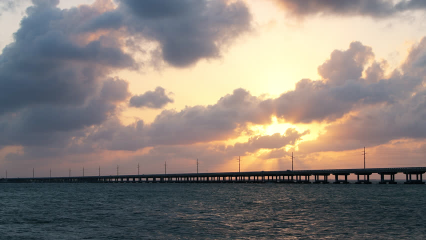 Dramatic orange cloudy sunset at seascape of Bahia Honda State Park in Florida Keys with old seven mile railroad bridge, overseas highway at gulf of mexico, clouds moving