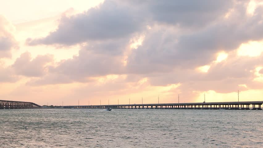 Sunset yellow clouds seascape in Bahia Honda State Park in Florida Keys with old railroad and seven mile bridge ocean and gulf of mexico with boat in water