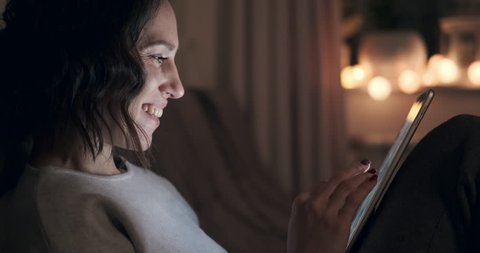 Happy woman using digital tablet at night