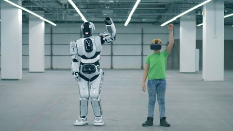 Human-like cyborg is lifting his arms after a boy in VR-glasses