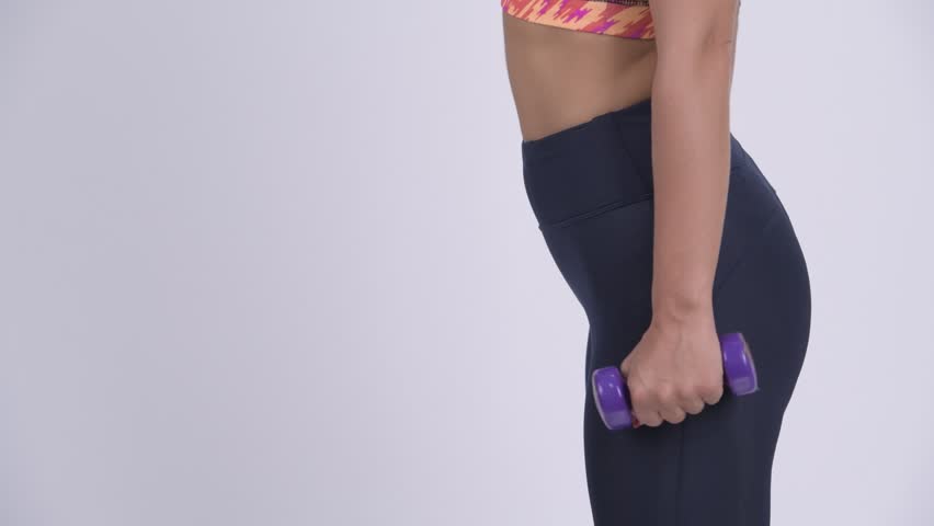 Profile view of young blonde woman exercising with dumbbells