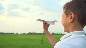 Happy Boy playing with paper airplane on the field over sunset background. Kid throws a paper plane, dream, freedom concept. Slow motion video footage 240 fps. Full HD 1080p. High speed camera 