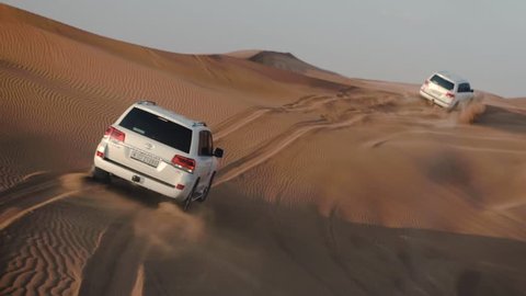 DUBAI UNITED ARAB EMIRATES - JANUARY 12 2019: Jeep Safari in the Arabian desert. Wiew out off moving car cabin window on forward luxury jeeps driving among fantastic desert tracks at sunset