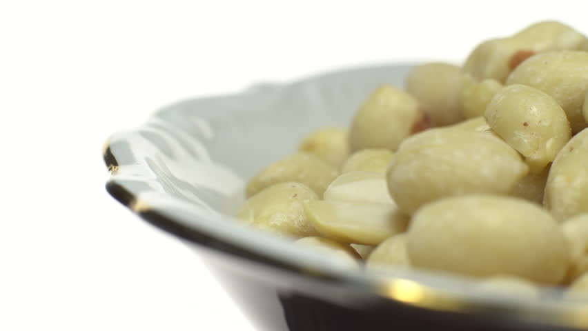 Raw peeled peanuts. 
Rotation. Snack closeup.  
Peanuts in a bowl. Selective focus.
Isolated on white. Studio shot.
Healthy food concept.
