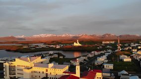 Sunset in Icelandic harbor, port in beautiful town with ocean, sea and church in background, 4k aerial drone footage, shots, Iceland, Stykkisholsmur
