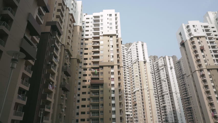 Wide shot of a huge residential apartment building block in Delhi, India. Camera pans right to reveal expanse of the massive buildings. Modern suburban life in India.