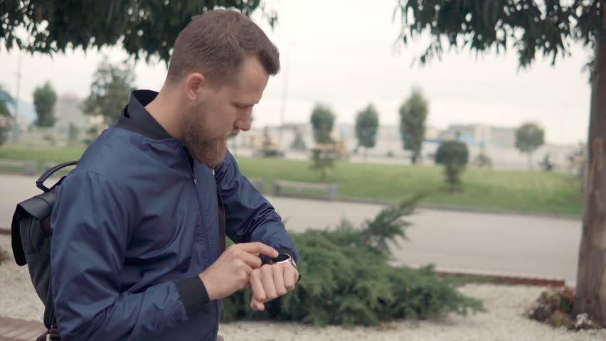 Side view shot of a guy checking statistics of his bicycle ride on his smartwatches. Man using smart devices outdoor.