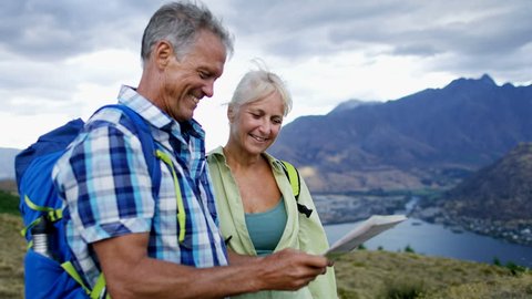 Active fit Caucasian male and female senior travellers enjoying their hiking and planning tour reading map of Mount Aspiring Lake Wakatipu New Zealand RED WEAPON