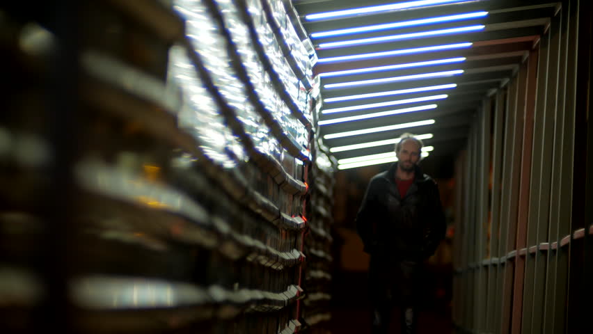 Lonely adult man in black cold coat walking at the night city with neon lights