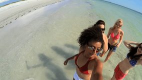 Happy young multi ethnic teens enjoying spring break on beach vacation ocean shallows greeting friends using social media shot on RED EPIC