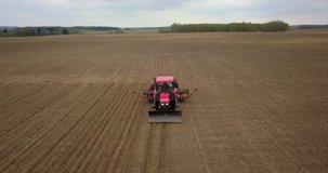 Farmer in tractor preparing land with seedbed cultivator. Agriculture. Tractor plowing field and preparing land for people who plant strawberry. Agronomy farming and husbandry concept. Aerial video.
