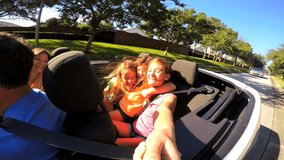 Caucasian family parents daughters siblings happy laughing holiday lifestyle enjoyment driving Cabriolet convertible vehicle travel tourism