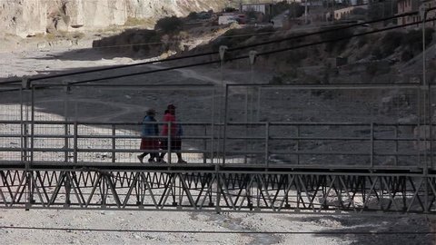 Iruya, Argentina - January 2022: Aboriginal Women Crossing Suspension Bridge over the Colanzuli River in Iruya, Salta Province, Argentina. 