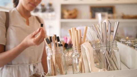 Young Mixed Race Woman Choosing Bamboo Eco Friendly Biodegradable Toothbrush in Zero Waste Shop. No plastic Conscious Minimalism Vegan Lifestyle. Reduce Reuse Recycle 4K Concept.