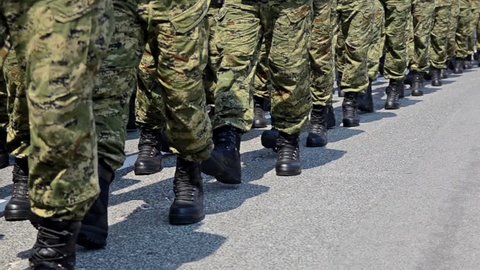 Soldiers with camouflage uniform and black boots marching in formation on parade at national holiday. Special police, guards and army forces on march at anniversary. Independence Day. Slow motion
