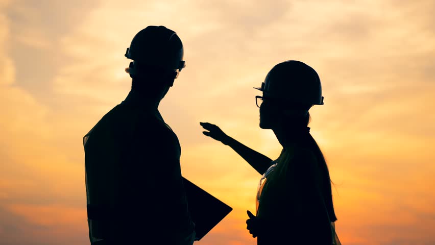 Constructors talking on a sunset background, close up.