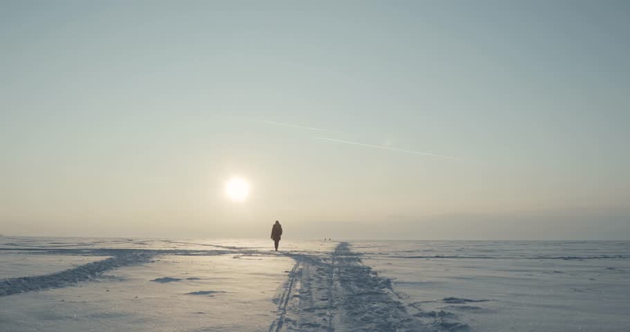 Young traveller goes through a blizzard at beautiful sunset. Polar expedition