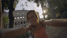 Selfie portrait of young woman in Rome enjoying travel in Italy and capturing a photo in front of the famous Colosseum