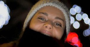 Happy woman with hat in winter at night on street making facetime video phone call