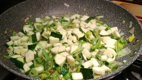 Preparation of a recipe with vegetables. zucchini cut into small pieces and the leek cut into strips cook in the pan, are added to other zucchini. 25fps 4K video