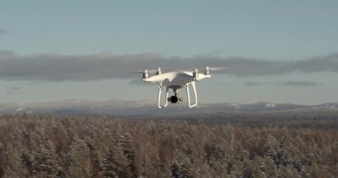 Ural Mountains, Bashkortostan / Russia - January 26 2019: Aerial View Drone DJI Phantom 4 Pro in flight from another drone over the forest mountains in winter frozen day. Reconnaissance drone.