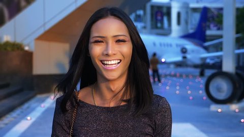 Beautiful blue-eyed asian girl ladyboy looking into the camera and smiling. transgender Thai model at the airport in the background of the aircraft