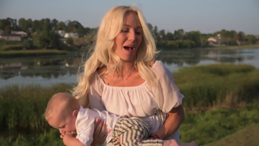 Walk around the lake of a beautiful young mother with her little son on a sunny day.