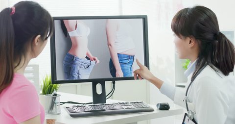 Plastic surgeon doctor explain liposuction to a patient with computer monitor in the clinic