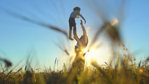 silhouette of father and son playing enjoying sunset in wheat field in nature on summer day. happy family walking outdoors. Little boy and father man having fun tossing up throwing son in air children