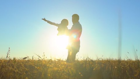 silhouette of father and son playing, enjoying sunset in wheat field in nature on summer day. happy family walking outdoors. child little boy, man having fun. father spinning around little son in arms