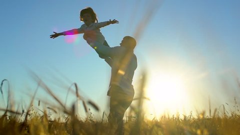 silhouette of father and son playing, enjoying sunset in wheat field in nature on summer day. happy family walking outdoors. Little child boy, man having fun. father spinning around little son in arms