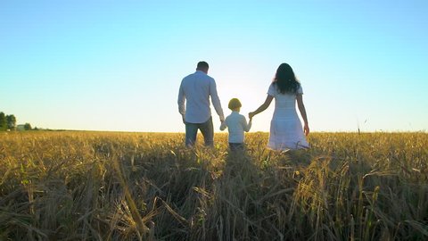 happy family outdoors walking on wheat field with little boy. Mother, father, son child having fun on summer day, enjoying nature together. health love travel summertime happy holiday happiness sunset