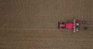 Farmer in tractor preparing land with seedbed cultivator. Agriculture. Tractor plowing field and preparing land for people who plant strawberry. Agronomy farming and husbandry concept. Aerial video.