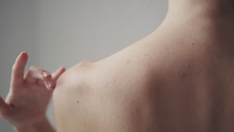 slender body of a girl close-up. a young woman touches her skin on her neck and shoulders.