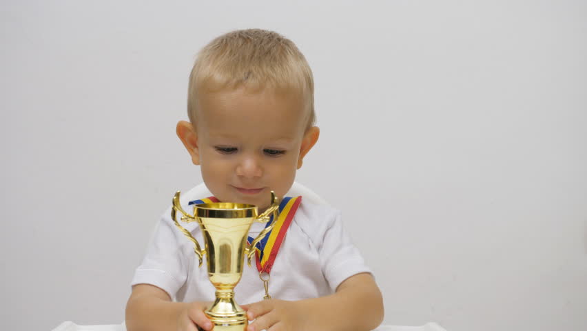 Portrait of baby child rising up golden cup, kid offering his victory trophy, generous attitude, conceptual Royalty-Free Stock Footage #1023376726